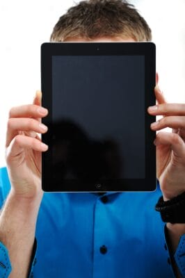 closeup-portrait-of-a-man-covering-his-face-with-ipad-SBI-300997423-scaled